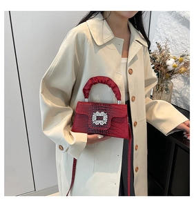 Close-up of red lizard texture handbag with rhinestone square buckle and ruched handle