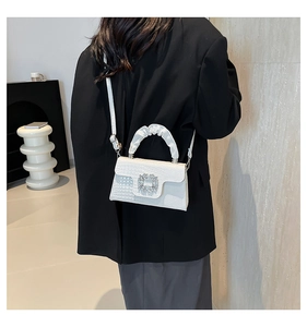 Detailed macro view of the lizard pattern white handbag with a sparkling crystal floral buckle