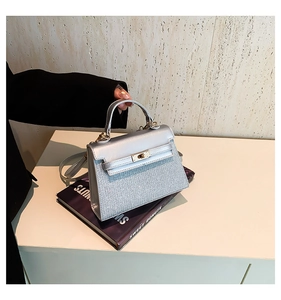 Detailed close-up of metallic silver finish and golden twist lock on Kelly style bag