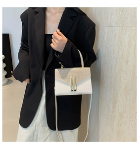 Details einer weißen Lederumhängetasche mit silbernen Pailletten und Goldschnalle am Model
