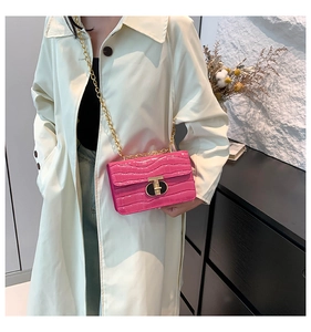 Detail of pink croc-embossed bag with gold T-lock and chain strap on shoulder