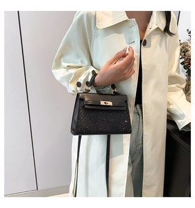 Black leather crossbody bag with glitter finish and gold hardware shown on light coat
