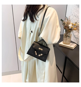 Detalle de bolso trapecio negro con lentejuelas y cierre dorado llevado por modelo