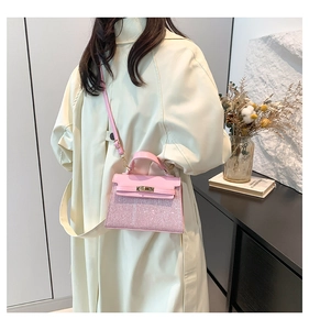 Close-up of pink glitter Kelly bag with gold hardware worn with a beige trench coat