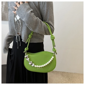 Détail du sac à main vert citron ondulé avec chaîne élégante en perles et cœurs argentés