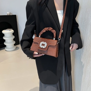 Brown lizard pattern handbag with crystal buckle and ruched handle on a black suit model