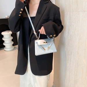 Silver glitter mini Kelly style handbag with gold clasp shown on a black suit model