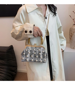 Detail of grey plaid handbag with pearl accents, bamboo handle, and gold metal clasp