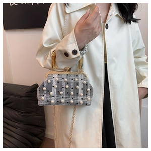 Detail of vintage plaid handbag with pearl embellishments and bamboo handle on a model