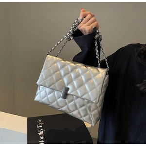 Détail d'un sac en cuir argenté matelassé avec finition métallisée et chaîne