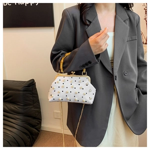 Detail of vintage pearl polka dot handbag featuring bamboo handle and golden chain strap