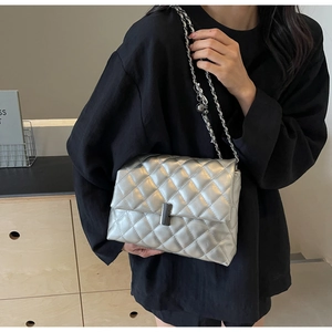 Détail du sac argenté matelassé avec bandoulière chaîne et fermoir métallique chic