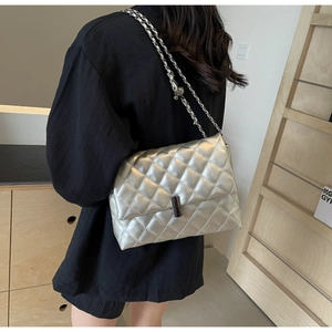 Détail d'un sac argenté matelassé avec texture métallique et fermoir rotatif chic