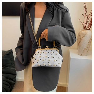 Close-up of white pearl polka dot bag with a natural bamboo handle and gold chain