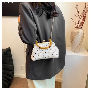 Detail showing white pearl-embellished handbag with bamboo handle and gold chain strap