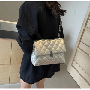 Sac argenté matelassé avec chaîne porté par un mannequin pour illustrer la taille réelle