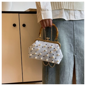 Close-up of vintage polka dot handbag with pearl accents and bamboo handle detail