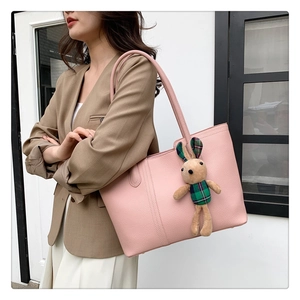 Borsa tote rosa con trama litchi e ciondolo a coniglio indossata da una modella