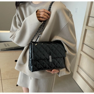 Détail de la texture en cuir verni matelassé et bandoulière en chaîne de sac à bandoulière