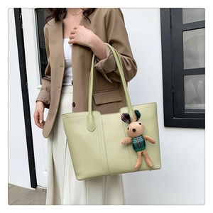 Dettaglio della borsa tote in pelle martellata verde chiaro con ciondolo a coniglietto