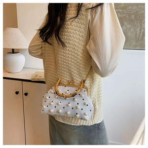 Detail of bamboo handle and pearl embellishments on the retro dotted crossbody bag