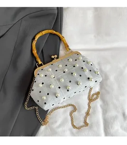 Detail of blue lace bag with white pearls, bamboo handle and gold chain strap
