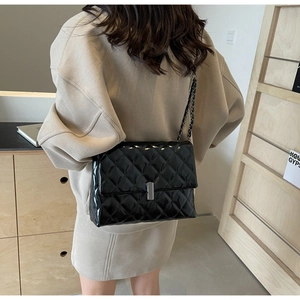 Sac matelassé en cuir verni noir avec boucle argentée et bandoulière chaîne à l'épaule