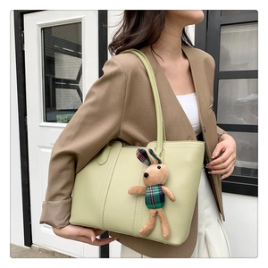Dettaglio della borsa tote verde chiaro con trama a grana e ciondolo a forma di coniglio
