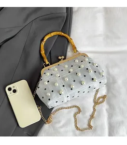 Detail of light blue mesh handbag with pearls, bamboo handle, and golden chain strap