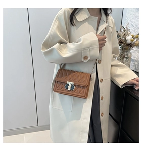 Petit sac bandoulière matelassé marron avec fermoir tournant sur un trench-coat beige