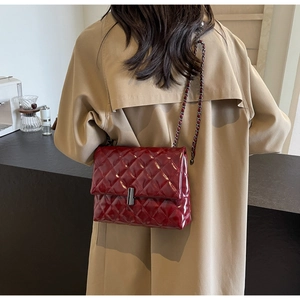 Gros plan sur le sac bandoulière matelassé bordeaux en cuir verni et chaîne en métal