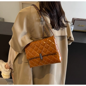 Gros plan d'un sac bandoulière matelassé marron avec chaîne et boule réglable