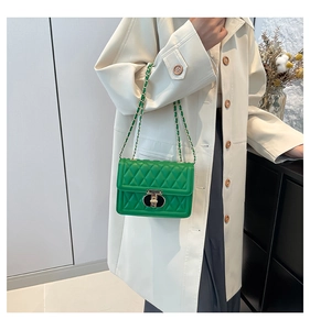 Détail du sac bandoulière vert matelassé avec fermoir métal sur trench-coat beige chic