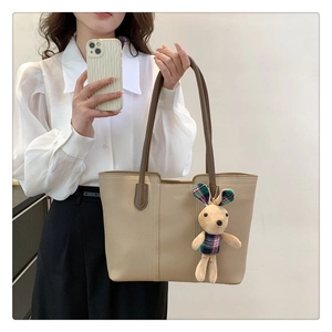 Dettaglio borsa tote in pelle beige con trama a grana e ciondolo a forma di coniglio