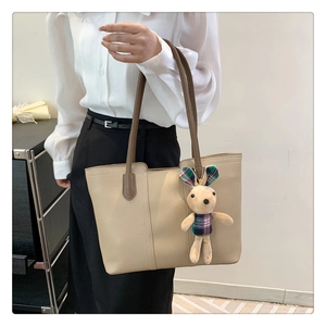 Dettaglio borsa tote beige in pelle martellata con grazioso ciondolo a coniglio