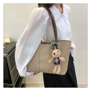 Dettaglio della borsa tote in pelle beige con ciondolo a forma di coniglio a scacchi