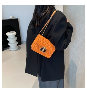 Détail du sac à main en cuir matelassé orange avec fermoir doré porté par un mannequin