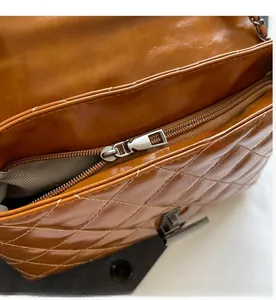 Détail macro de la fermeture éclair en métal argenté et surpiqûres du sac en cuir marron