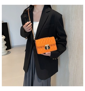 Détail macro du sac matelassé orange avec fermoir métallique et bandoulière chaîne