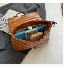 Intérieur spacieux du sac bandoulière matelassé marron contenant tablette et objets du quotidien