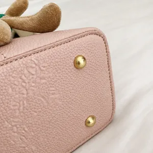Dettaglio del fondo della borsa in pelle litchi rosa con piedini protettivi in metallo