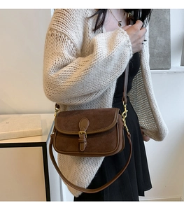 Close-up of brown suede crossbody bag styled with a beige cardigan for an autumn look
