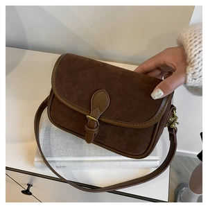 Close-up of vintage dark brown suede crossbody bag featuring retro strap detail