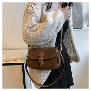 Close-up of brown suede crossbody bag showing vintage gold buckle and fine leather texture