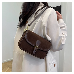 Close-up of retro dark brown suede saddle bag worn with a beige trench coat