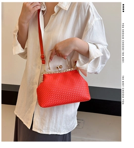 Detail of red woven leather handbag with gold pearl clasp and chain handle worn by model
