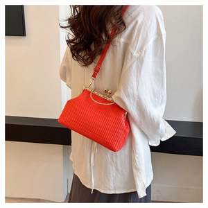 Close-up of bright orange woven crossbody bag with vintage gold metal clasp detail