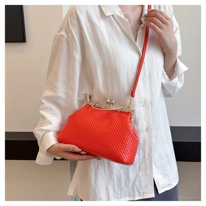 Detail of red woven clutch bag with pearl clasp and slim leather shoulder strap