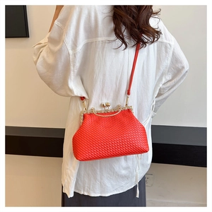 Red woven crossbody bag with metal frame clasp worn by model over a white shirt