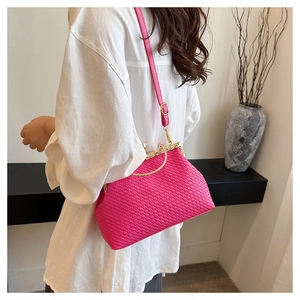 Detail of rose pink woven leather handbag with gold metal clasp on a model shoulder
